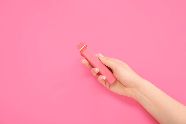 Woman holding electronic cigarette on pink background - Photo, Image