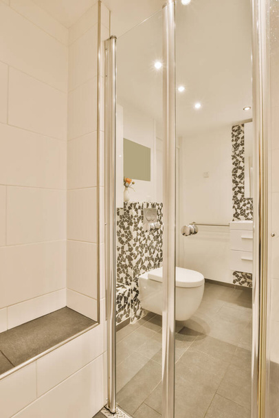 Modern bir banyo. Duvarları, zemini ve duşu aynanın önünde siyah beyaz fayanslarla kaplı. - Fotoğraf, Görsel