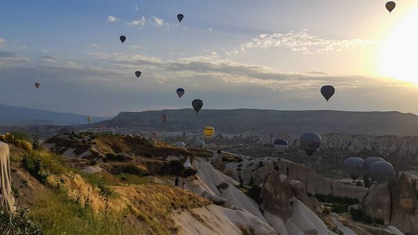 Hot air balloon flying over rock landscape at Cappadocia Turkey. Cave house in Uchisar village,  - Foto, afbeelding