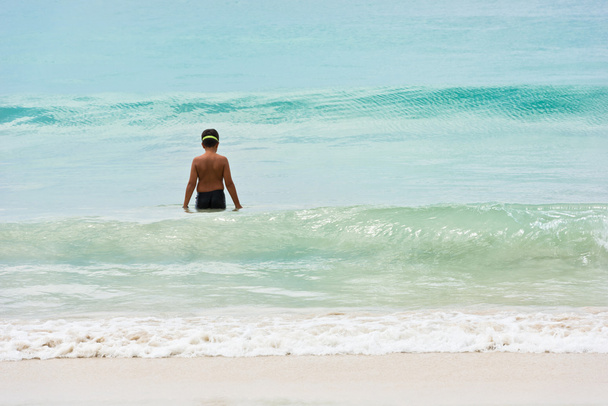 A young boy stands at the ocean shore - Foto, Imagem