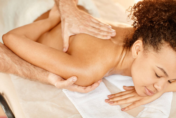 Zbliżenie portret młodej czarnej kobiety korzystającej z masażu pleców w relaksującej sesji SPA i uśmiechnięty - Zdjęcie, obraz