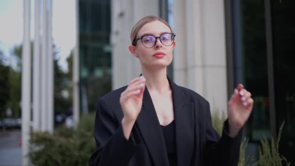 ヨーロッパのビジネスマンの少女は彼女のメガネを調整し,カメラに頭を回します - 映像、動画