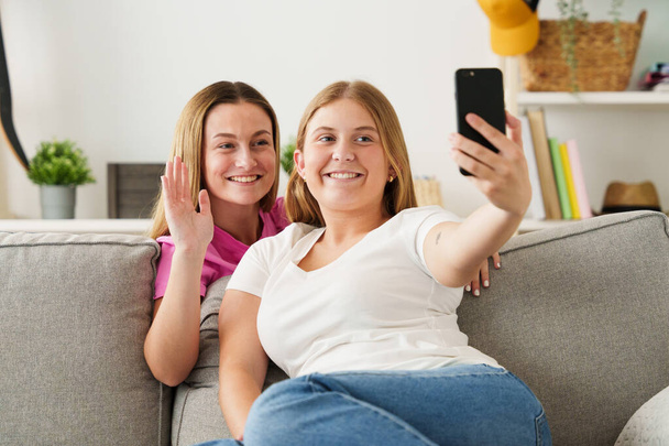 Две молодые женщины делают селфи по телефону. Подростки, имеющие видеозвонок. - Фото, изображение
