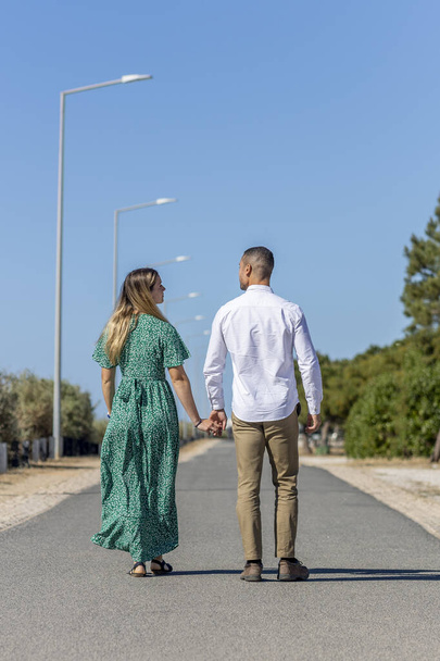 Bliski widok szczęśliwej młodej europejskiej pary trzymającej się razem na asfaltowej drodze. - Zdjęcie, obraz