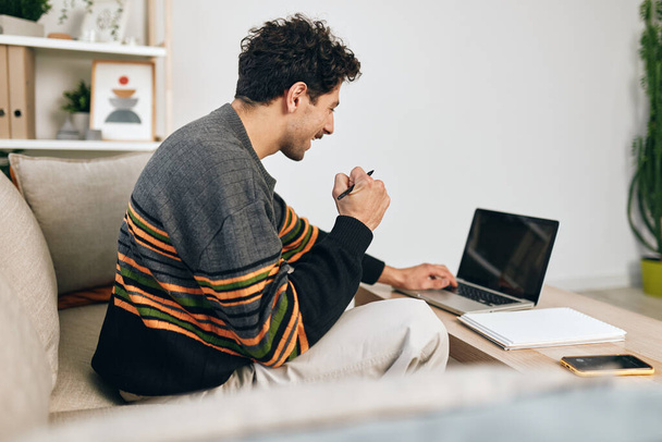 Muž pohledný moderní vzdělávání relaxace na volné noze pracovní gauč laptop počítač muž úsměv emoce internet mladý obchod on-line technologie domácí hledá - Fotografie, Obrázek