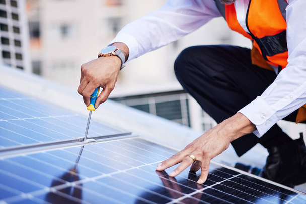 Solar panels, person hands and screwdriver for engineering maintenance, sustainability and development on rooftop, Industry worker with eco friendly grid, tools and photovoltaic installation in city. - Photo, Image