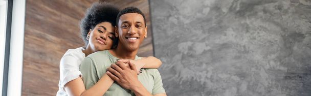 喜びのアフリカ系アメリカ人女性は,新しい家で笑顔のボーイフレンドを抱擁, バナー - 写真・画像