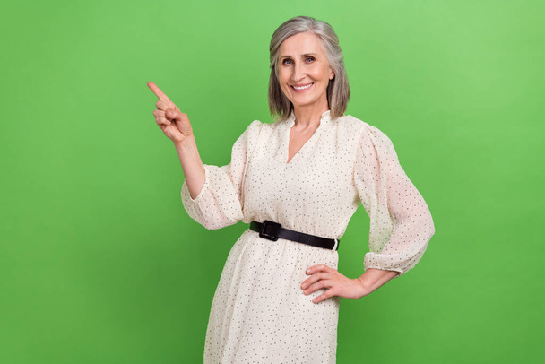 Photo portrait of attractive old woman finger point empty space promotion dressed stylish white clothes isolated on green color background. - Fotó, kép