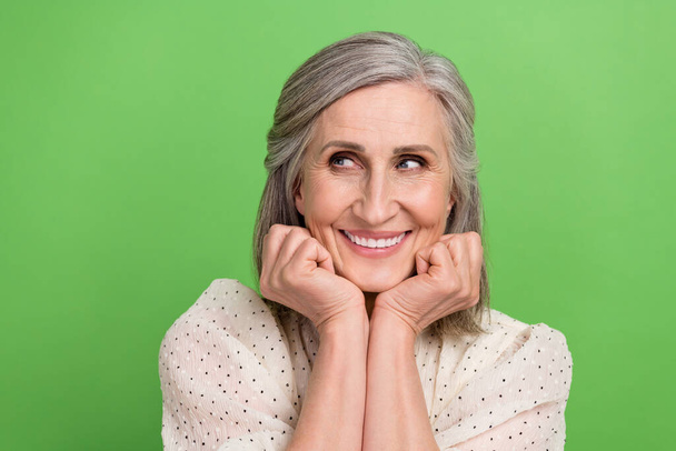Photo portrait of lovely retired lady fists face look interested empty space wear trendy white outfit isolated on green color background. - Foto, Imagen