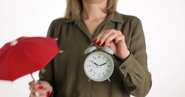 La mujer sostiene el despertador y el paraguas rojo. Protección y seguridad del tiempo personal - Imágenes, Vídeo