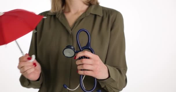 Γυναίκα με ομπρέλα και ιατρικό στηθοσκόπιο. Προστασία της υγείας και ασφάλιση - Πλάνα, βίντεο