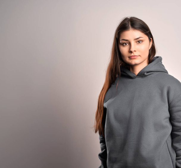 Brunette woman wearing a sweatshirt with a hood. Beautiful girl blank one color jumper. - Valokuva, kuva