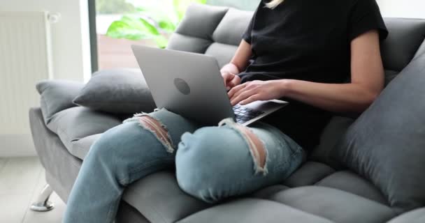 Nainen, jolla on kannettava tietokone, istuu kotona sohvalla. Etätyö ja freelance - Materiaali, video
