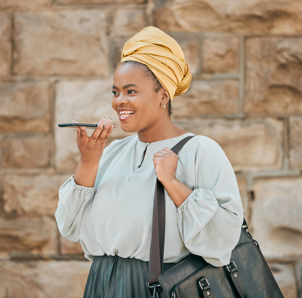 Young woman on loudspeaker phone call in the city walking in urban street with a briefcase. Voice note, technology and African female designer recording audio memo or message on a cellphone in town - Photo, Image