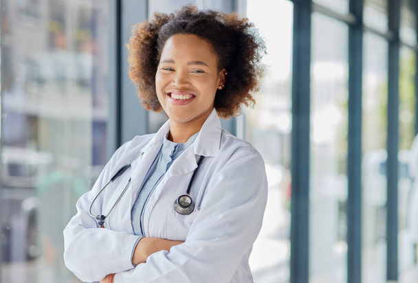 Happy black woman, portrait and doctor with arms crossed in clinic for wellness services, help or medical consulting. Medicine, healthcare and young female professional working with trust in hospital. - Photo, Image