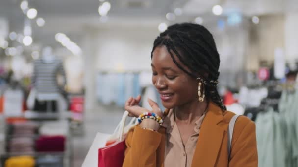 Retrato de menina afro-americana desfrutando de suas compras, ela sorrindo para a câmera de pé com sacos de compras - Filmagem, Vídeo