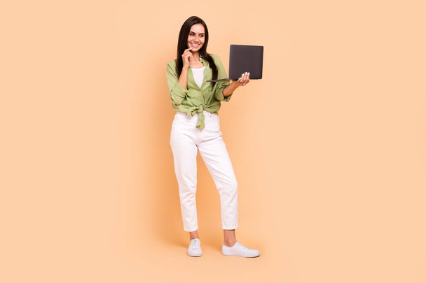 Full length photo of optimistic clever nice woman wear green shirt holding laptop finger on lips isolated on beige color background. - Foto, imagen