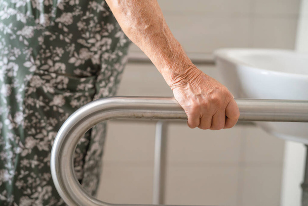 Asiatique femme âgée patient utilisation toilettes salle de bain poignée sécurité dans l'hôpital de soins infirmiers, concept médical fort sain. - Photo, image