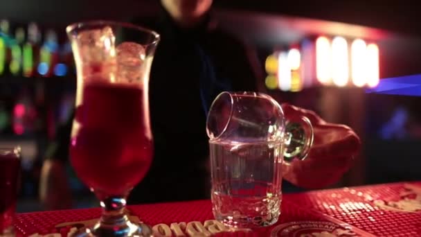 4K Profi férfi csapos kevert kék likőrkoktél italt tölt koktélkeverőből feles pohárba a bárpulton a nightclubban. Mixológus csapos, aki alkoholos italt szolgál fel az ügyfélnek. - Felvétel, videó