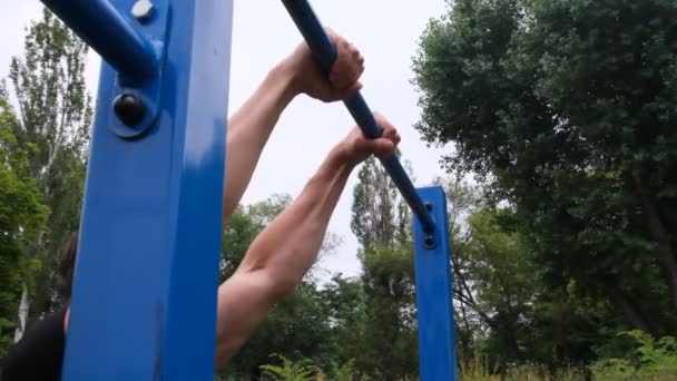 portrait of a young man doing pull-ups on the horizontal bar outdoors on a street playground, a strong athlete, a healthy man, a horizontal bar on the street. sports guy, Street Workout - Footage, Video
