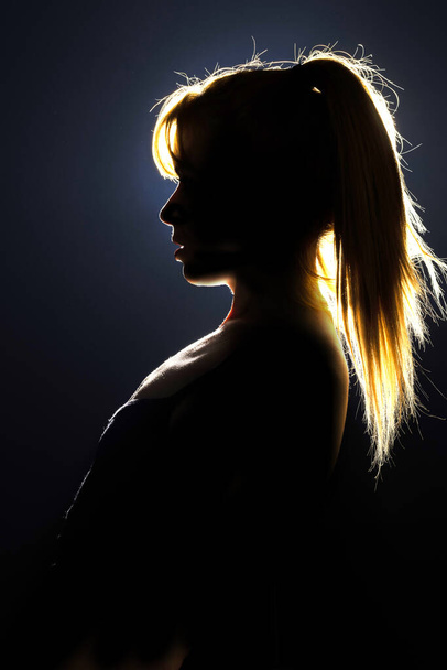 Silhouette of woman's head with ponytail, back light. - Fotografie, Obrázek
