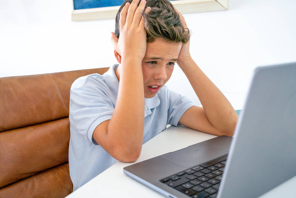 stresu dospívající chlapec studuje s notebookem, zatímco sedí na stole doma - Fotografie, Obrázek