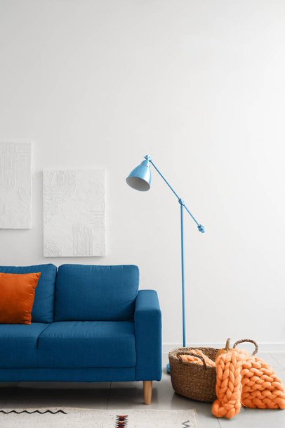 Інтер'єр світлої вітальні з синім диваном і лампою - Фото, зображення