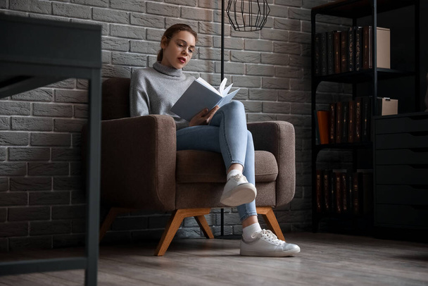 junge Frau liest Buch im Sessel zu Hause - Foto, Bild