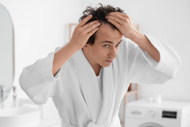 Młody człowiek z problemem wypadania włosów w łazience - Zdjęcie, obraz
