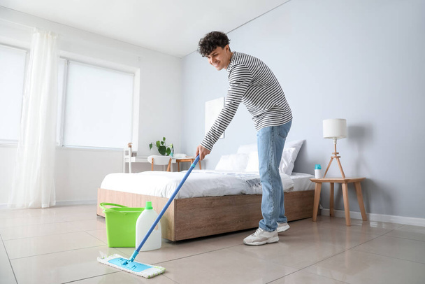 Young man mopping floor in bedroom - Photo, Image
