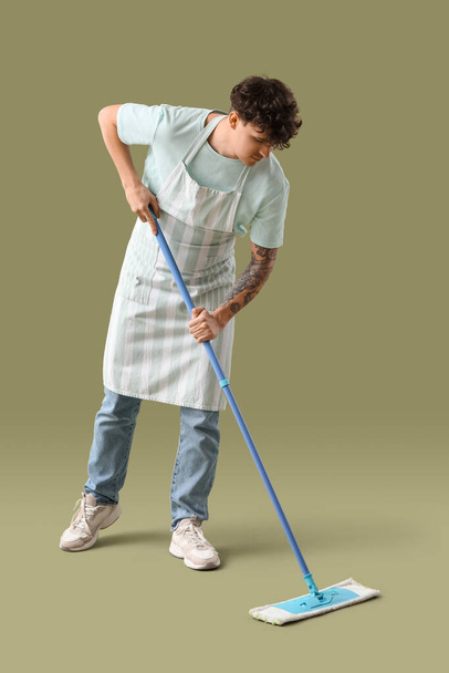 Young man with mop on green background - Foto, Imagen