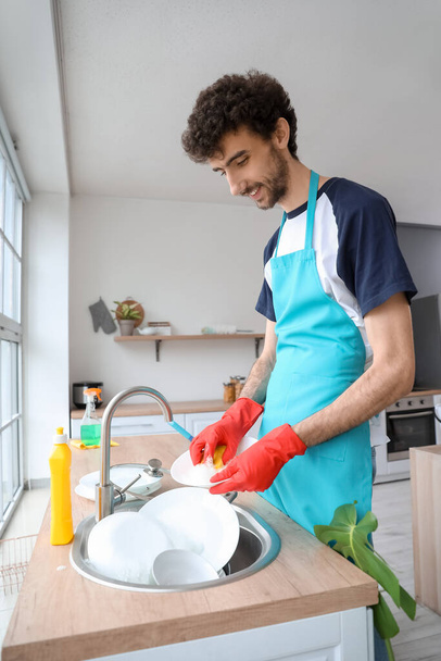 Young man washing dishes in kitchen - Foto, Imagem