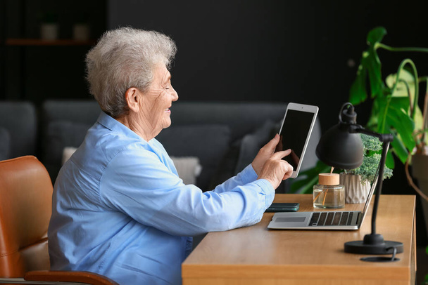 Старшая женщина использует планшетный компьютер дома
 - Фото, изображение