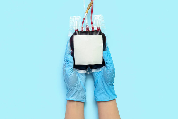 Vrouwelijke arts met bloedverpakking op blauwe achtergrond. Werelddonordag - Foto, afbeelding