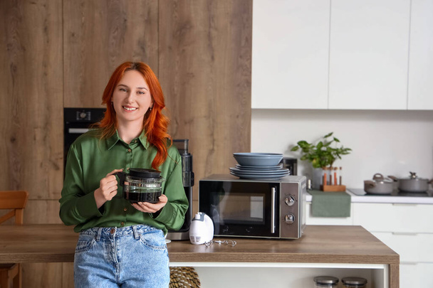 Giovane donna rossa con caffettiera in cucina moderna - Foto, immagini