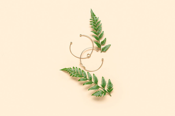 Beautiful bracelets and plant leaves on beige background - Foto, Imagen
