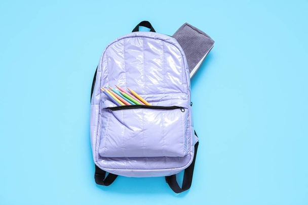 Lila iskolai hátizsák papírral, kék háttér - Fotó, kép