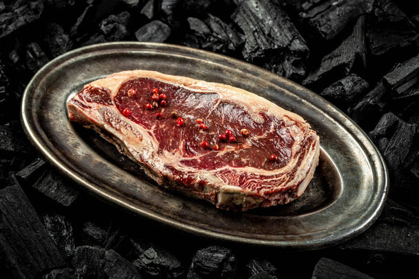 marbled beef New York steak on BBQ grill coal. Fresh meat for grilling. steak raw striploin of beef. top view. place for text. - Photo, Image