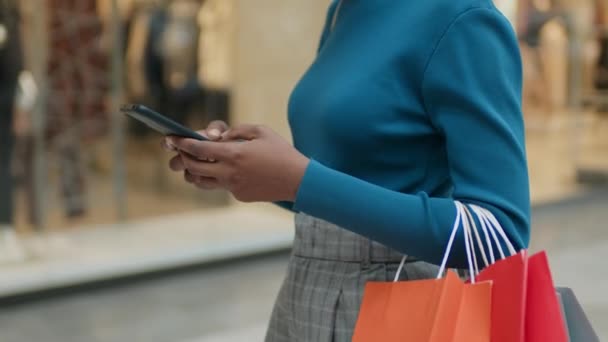 Primo piano di shopaholic con shopping bag sms messaggio sul telefono cellulare mentre si cammina vetrine - Filmati, video