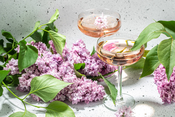 Ροζέ κρασί σε γυάλινο και λιλά λουλούδια σε λευκό φόντο, καλοκαιρινή γιορτή, γαμήλια ευχετήρια κάρτα, πρόσκληση έννοια, - Φωτογραφία, εικόνα