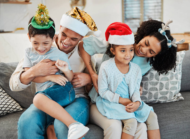Parents, kids and playing on sofa, christmas or tickling with comic laughing, game or excited in family home. Mother, father and happy young children with xmas celebration, relax and bonding or couch. - Photo, Image