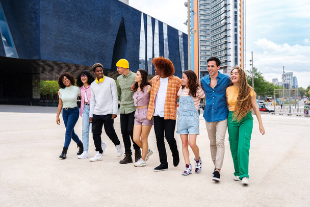 Happy playful multiethnic group of young friends bonding outdoors - Multiracial millennials students meeting in the city, concepts of youth, people lifestyle, diversity, teenage and urban life - 写真・画像