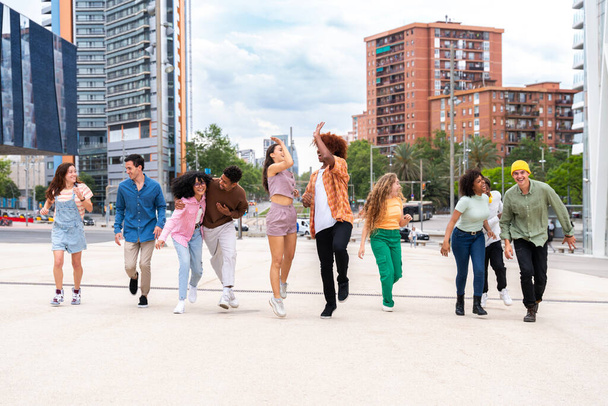 Happy playful multiethnic group of young friends bonding outdoors - Multiracial millennials students meeting in the city, concepts of youth, people lifestyle, diversity, teenage and urban life - Photo, Image