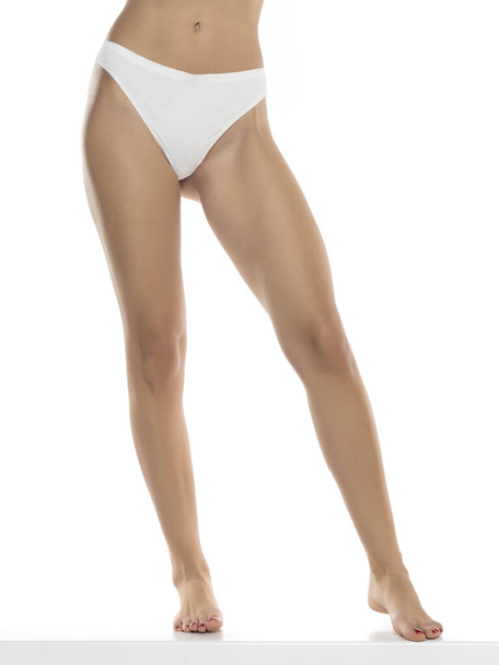 Perfecte vrouwelijke benen in ondergoed op een witte studioachtergrond. Vooraanzicht - Foto, afbeelding