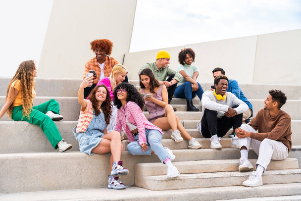 Happy playful multiethnic group of young friends bonding outdoors - Multiracial millennials students meeting in the city, concepts of youth, people lifestyle, diversity, teenage and urban life - Foto, Bild