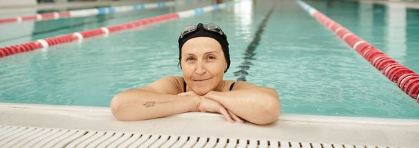 joyeuse femme d'âge moyen se relaxant au bord de la piscine, bonnet de bain et lunettes, centre de loisirs, bannière - Photo, image
