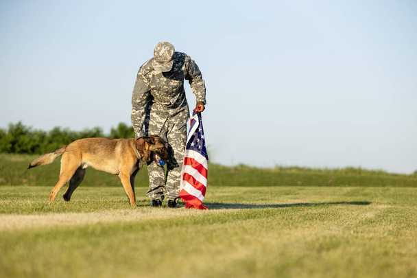 USA marine soldier standing by his military dog and holding flag. - Photo, Image
