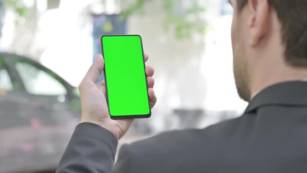 Młody biznesmen korzystający z telefonu z zielonym ekranem na zewnątrz - Materiał filmowy, wideo
