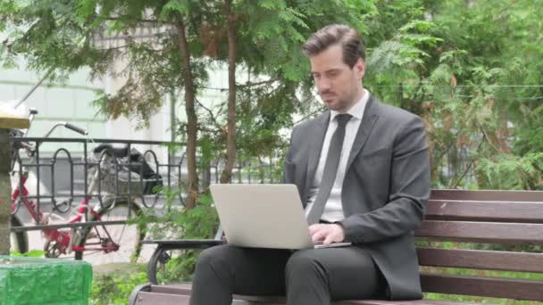 Uomo d'affari di mezza età con mal di testa che lavora sul computer portatile all'aperto - Filmati, video
