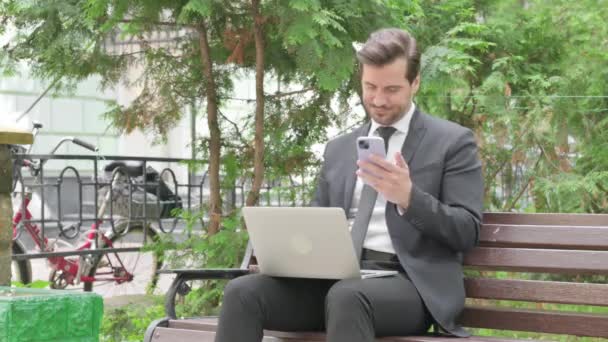 Középkorú üzletember Laptopon és okostelefonon dolgozik - Felvétel, videó